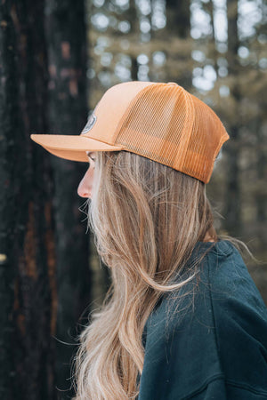 Hiking Boot, Trucker Hat worn by a woman outdoors, showcasing a stylish orange trucker hat designed in Canada.