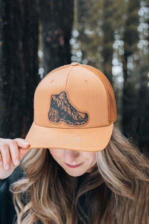 Hiking Boot, Trucker Hat worn by a woman in outdoor setting, designed in Canada, featuring Canadian artist illustration.
