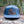 Hiking Boot, Flat Bill Hat displayed on a log in a forest, featuring a faux leather patch and mountain design.