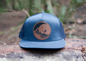 Moon and Climber Flat Bill Hat featuring durable faux leather patch in a natural setting.