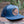 Moon and Climber Flat Bill Hat on a log, featuring a faux leather patch and a stylish design for outdoor adventures.