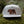 Mountain Bear Flat Bill Hat displayed on moss with a durable faux leather patch, ideal for outdoor adventures.