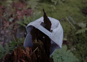 Mountain Bear Trucker Hat resting on a log surrounded by nature, designed in Canada for outdoor adventures.