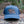 Mountain Bear Trucker Hat on a log in nature, designed for outdoor adventures, by a Canadian artist.