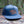 Mountain Bear Flat Bill Hat on a log, featuring a durable faux leather patch and breathable mesh back.