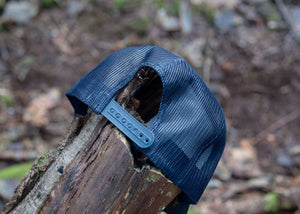 Mountain Bear Trucker Hat showcasing adjustable snapback on a log in the outdoors, perfect outdoor hat for women.