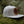 Sea to Sky flat bill hat on mossy ground, featuring faux leather patch and perfect for outdoor adventures.