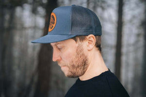 The Sea to Sky flat bill hat worn by a man, showcasing faux leather patch and adjustable snapback design.