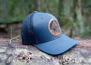 Sea to Sky Trucker Hat with faux leather patch on natural background, designed in Canada for outdoor adventures.