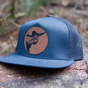 Snowboarder, Flat Bill Hat featuring a durable faux leather patch on a trucker hat, perfect for outdoor adventures.