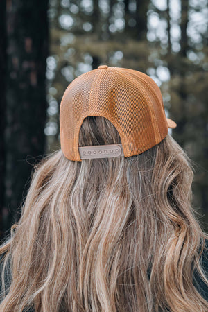 Hiking Boot, Trucker Hat with adjustable snapback closure shown on a woman outdoors in Canada.