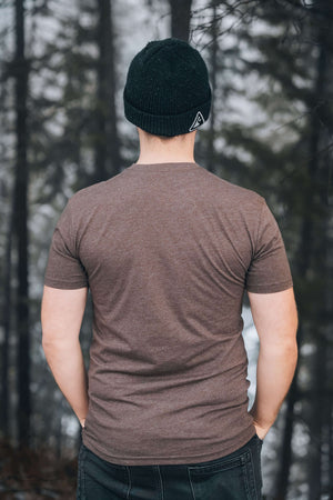 Back view of a man wearing a Wolf, Unisex T-shirt, Responsibly Made in a forest setting.