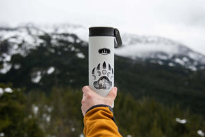 Bear Claw Sticker on a travel tumbler held against a snowy mountain backdrop, perfect outdoor sticker for adventure lovers.