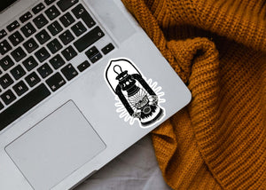 Camping Lantern Sticker on a laptop, a black and white outdoor sticker designed by a Canadian artist.