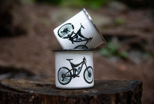 Mountain Bike Enamel Mug - Two enamel mugs featuring an original illustration of a mountain bike in a natural setting.