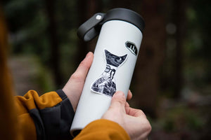 Person holding a white travel tumbler featuring a Chemex Sticker with original black and white illustration.