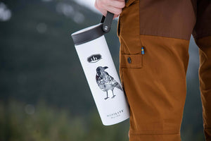 Crow Sticker on a white travel tumbler held by a person in outdoorsy attire, showcasing a black and white original illustration.