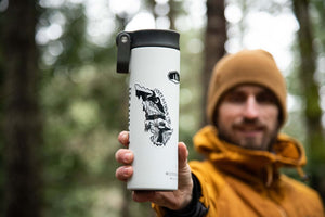 Jasper National Park Sticker on a travel tumbler held by a man in the forest, showcasing the durable outdoor sticker design.