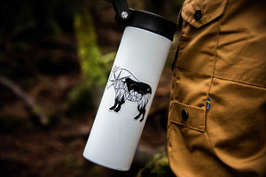 Mountain Goat Sticker on a white travel mug held by a person in nature, showcasing an original illustration.