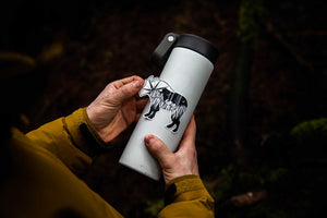 Person holding a water bottle featuring a Mountain Goat Sticker, showcasing a black and white original illustration.