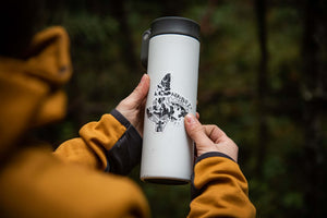Nunavut Sticker on a white travel tumbler held outdoors by a person in a yellow jacket.