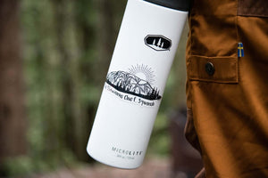 The Stawamus Chief Sticker on a white water bottle in a natural outdoor setting, featuring an original illustration.