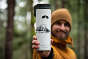 The Stawamus Chief Sticker displayed on a MICROLITE tumbler held by a smiling outdoorsman in a forest.