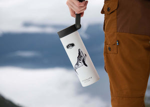 Whale Sticker on a stylish thermos held by a person in outdoor attire against a mountain backdrop.