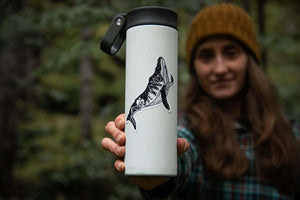 Whale Sticker on a travel mug held by a woman in a forest, showcasing original illustration, outdoor sticker.